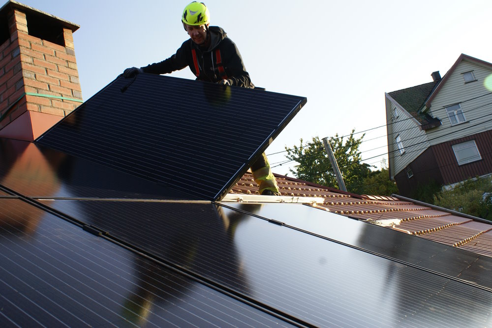 Person installiert Solarpanel auf Dach